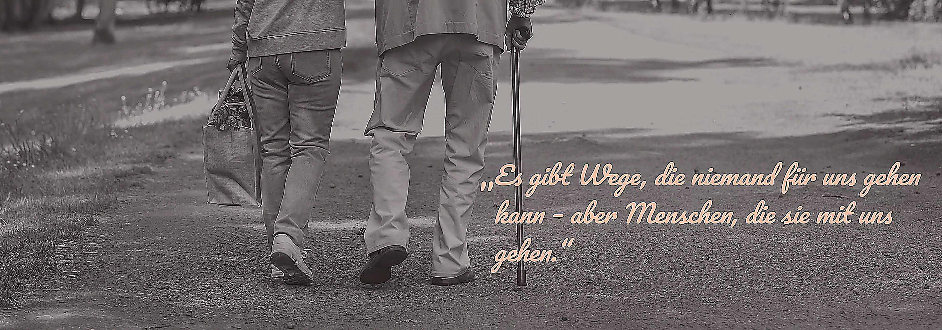 Eine Pflegekraft begleitet einen älteren Menschen beim Spaziergang. Bildunterschrift: Es gibt Wege, die niemand für uns gehen kann – aber Menschen, die sie mit uns gehen.